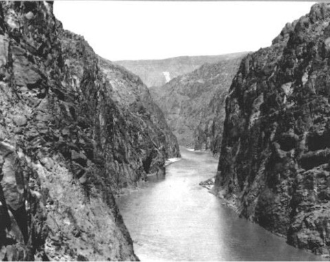 A black and white picture of a river flowing through a canyon.